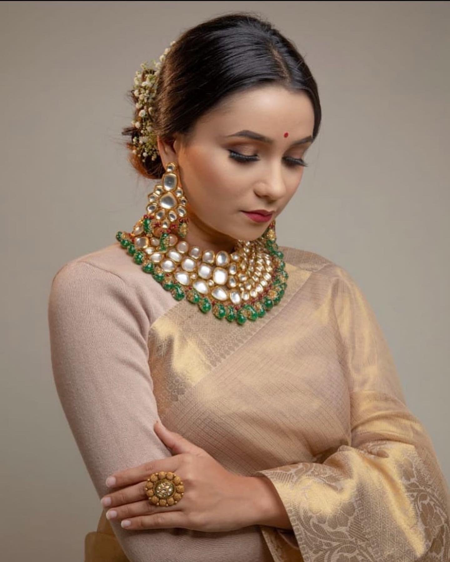 Hitakshi Chatterjee in bridal kundan jewellery and a gold-toned saree, looking down