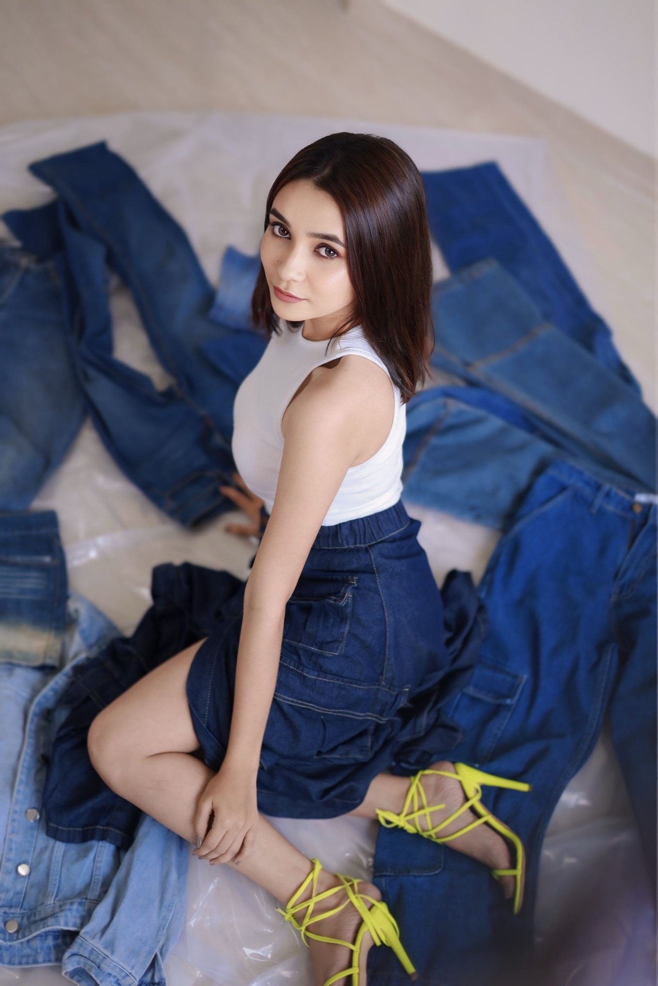 Hitakshi Chatterjee seated amid a spread of denim pieces, styling shoot