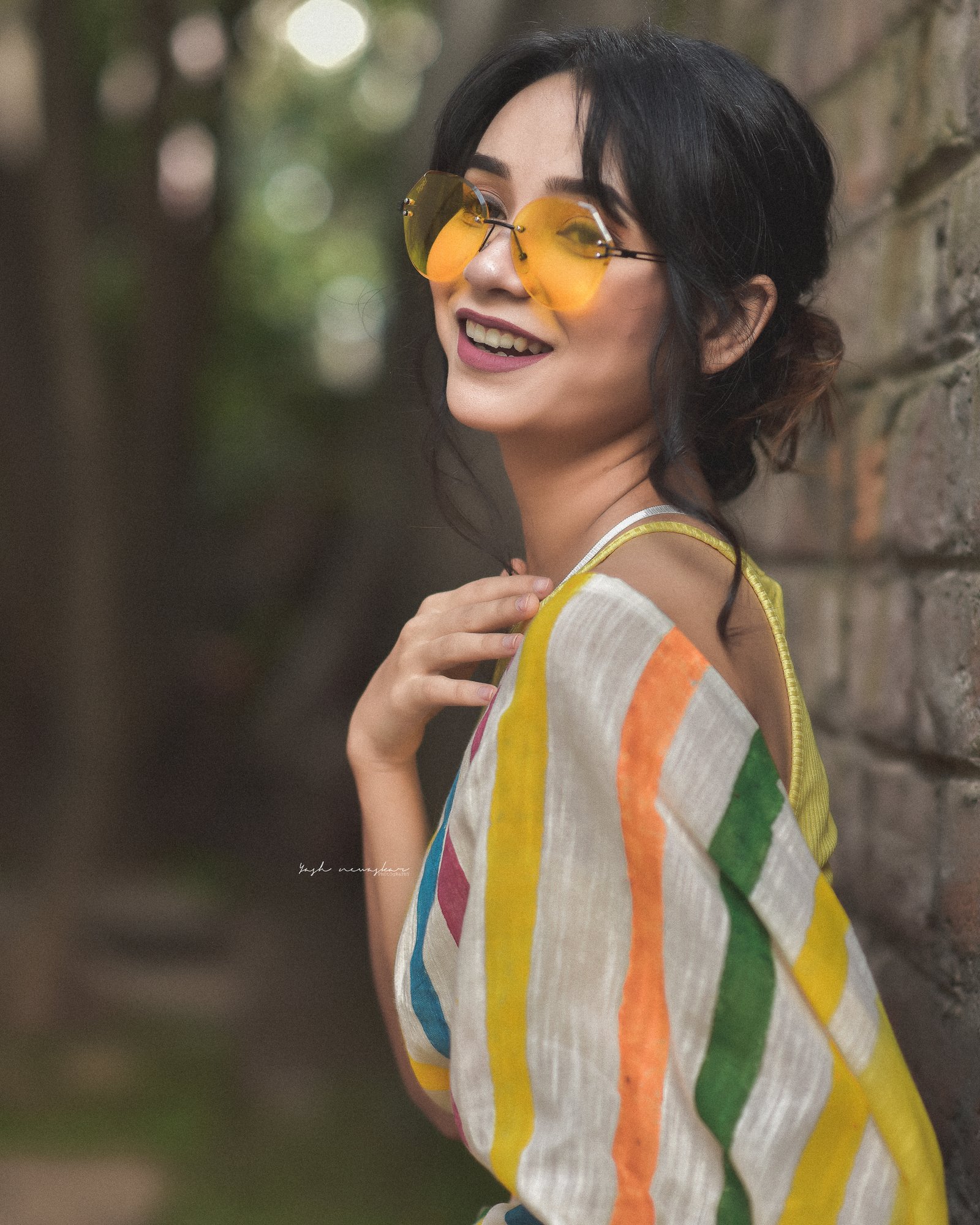 Hitakshi Chatterjee in a colourful striped saree and tinted sunglasses