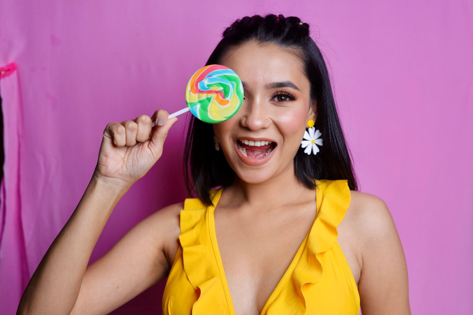 Hitakshi Chatterjee in a yellow ruffle dress with a rainbow lollipop, playful beauty shoot
