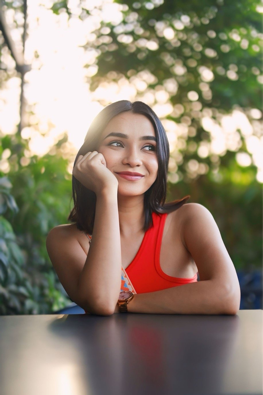 Hitakshi Chatterjee at a café table in a red top, golden hour lifestyle shoot